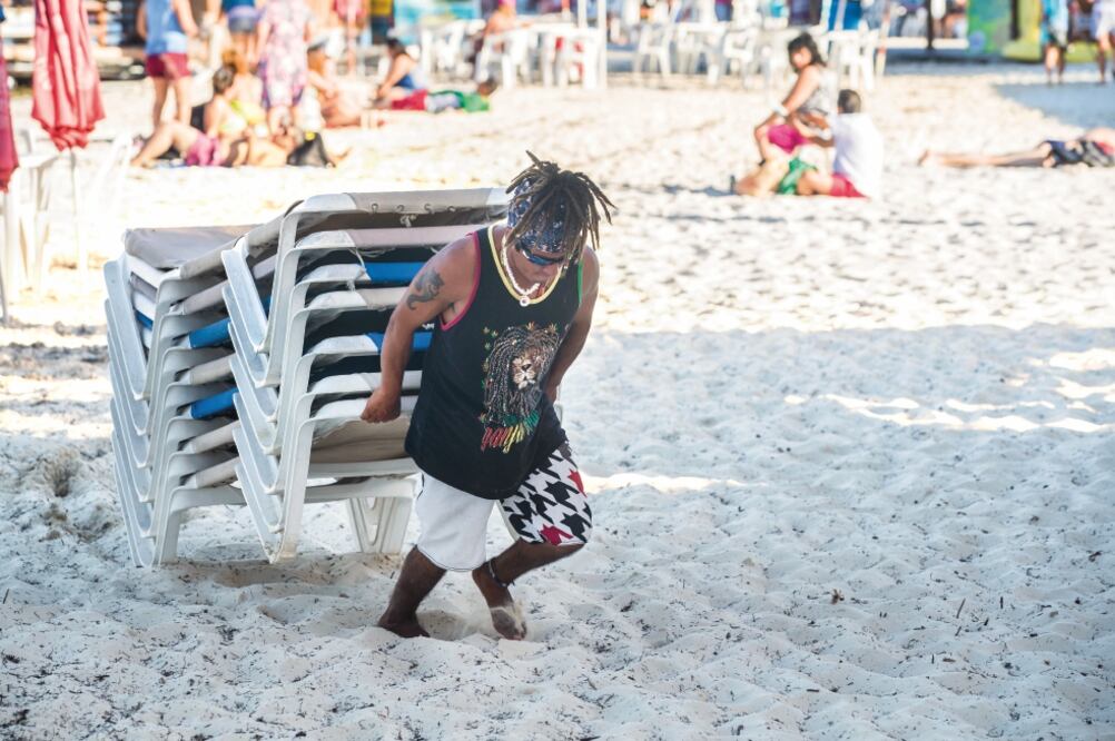 Javier, conocido como El Rastas, llegó de Honduras con la esperanza de estudiar para chef y trabajar en un crucero. Gana 100 pesos diarios por acomodar camastros (GERMÁN ESPINOSA)