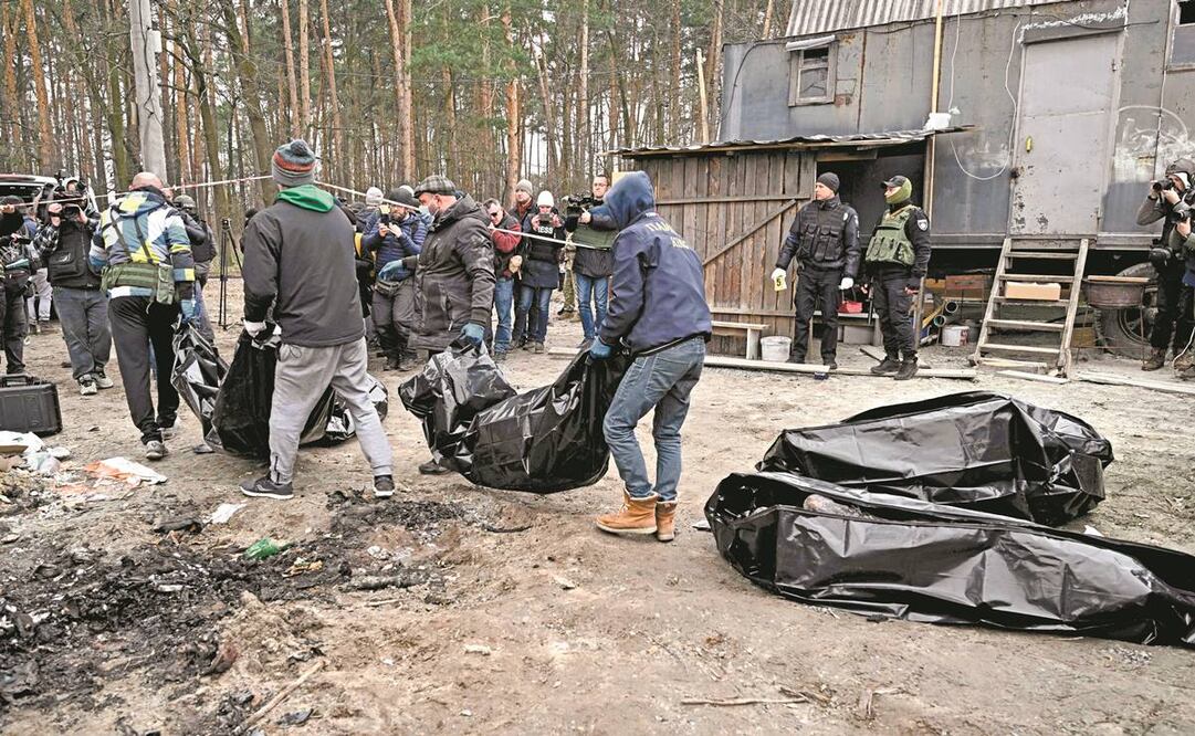 Empleados ucranianos recogen los cuerpos calcinados de seis personas asesinadas en Bucha, a las afueras de Kiev. Uno de los cadáveres era de un niño. Foto: Genya Savilov/ AFP.