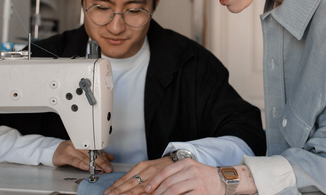 Joven cose un vestido. Fuente: Pexels