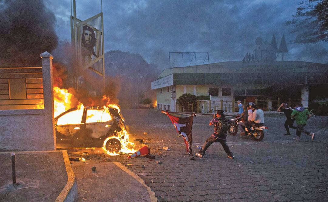 Un hombre lanza una bandera del partido del actual gobierno nicaragüense hacia un vehículo en llamas, durante las protestas de ayer en Managua (JORGE TORRES. EFE)