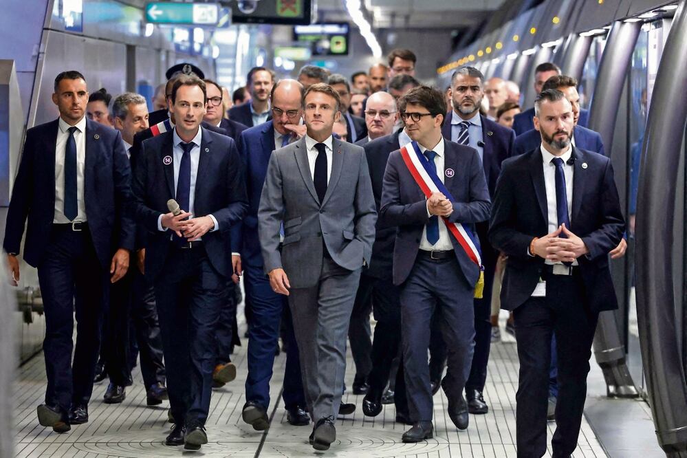 El presidente de Francia, Emmanuel Macron (centro), con funcionarios sobre un andén de la estación del Metro Mairie de Saint-Ouen, antes de la inauguración de la parada Saint-Denis Pleyel y la ampliación de la
línea 14 en París. Foto: Yves Herman AFP