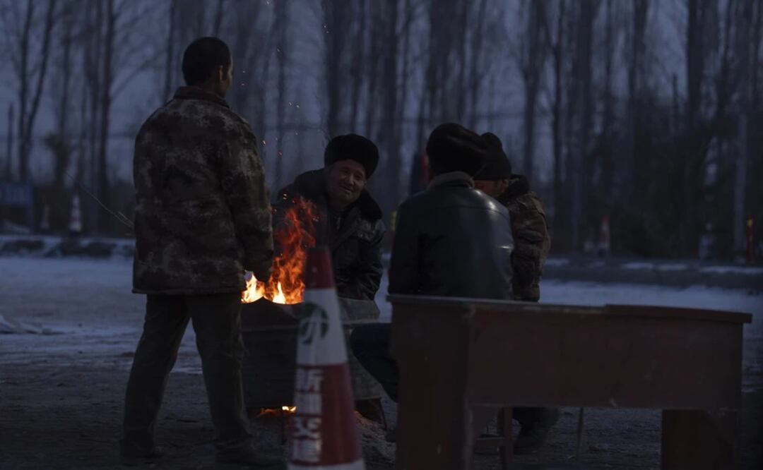 Hombres reunidos en torno a una hoguera en un control de carretera para entrar en el condado Wushi en la región occidental china de Xinjiang. Foto: AP