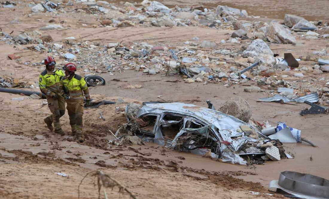 Los trabajadores de rescate pasan junto a un automóvil destruido medio enterrado después de las inundaciones en Paiporta, cerca de Valencia, España, el domingo 3 de noviembre de 2024. Foto: AP