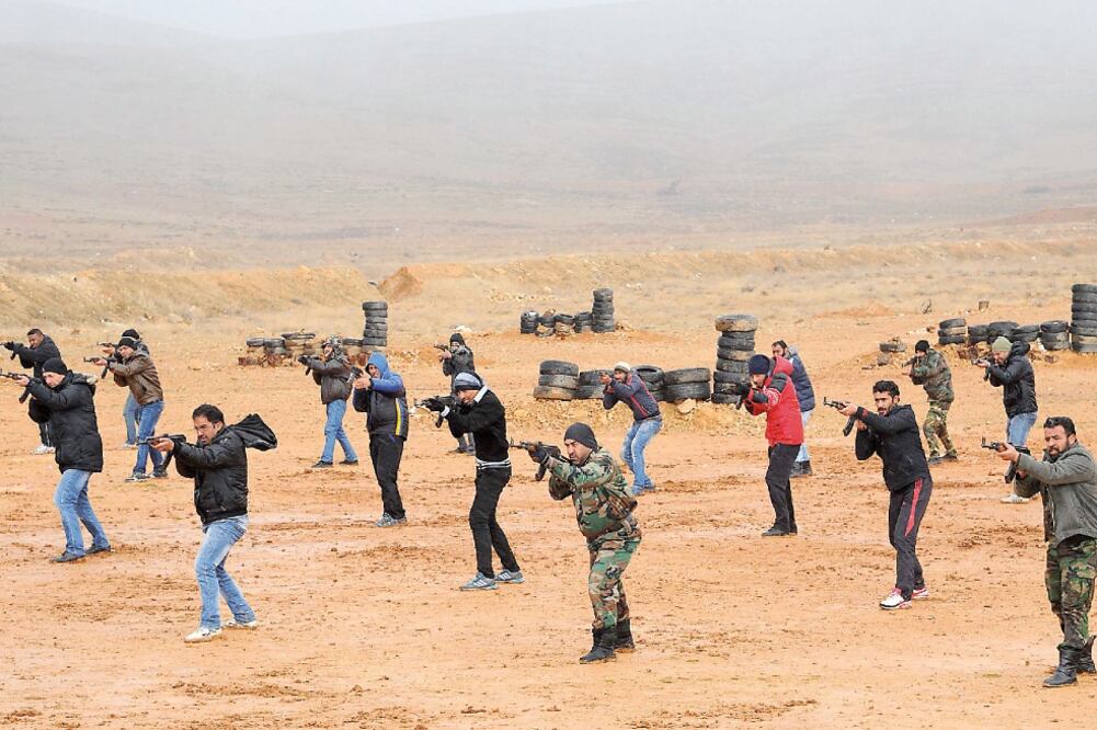 Un grupo de combatientes leales al gobierno sirio de Bashar al-Assad, durante un desfile militar para celebrar la finalización de su entrenamiento en la provincia de Quneitra, en el sureste de esa nación (AMMAR. XINHUA)