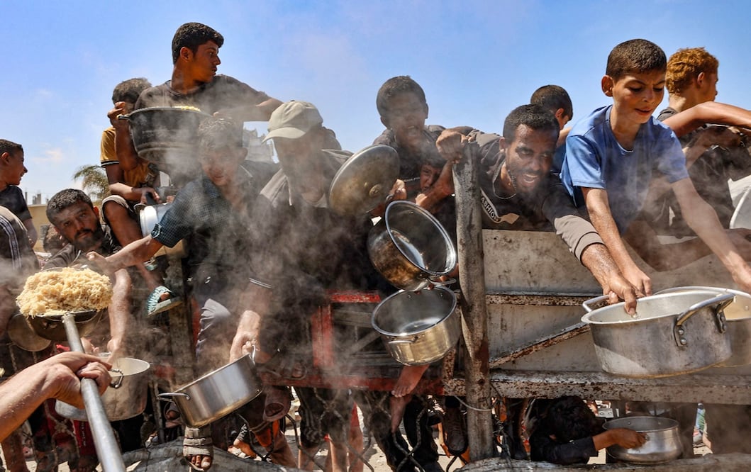 Hombres y niños palestinos extienden sus ollas vacías para recibir comida en Gaza, el 23 de agosto de 2025. Naciones Unidas culpa a Israel de "obstrucción sistemática" durante más de 22 meses de guerra. Foto: AFP
