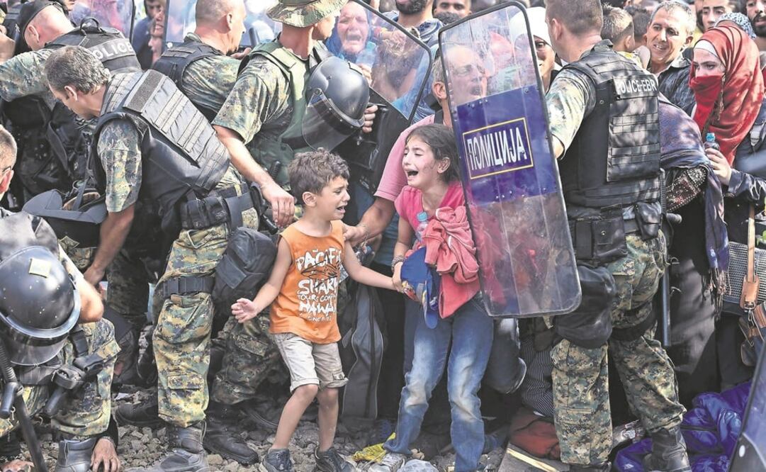 Dos niños migrantes lloran mientras otros refugiados intentan romper el cordón policial para cruzar a la Macedonia procedentes de Grecia el año pasado. (Foto: Archivo - EFE/Georgi Licovski)