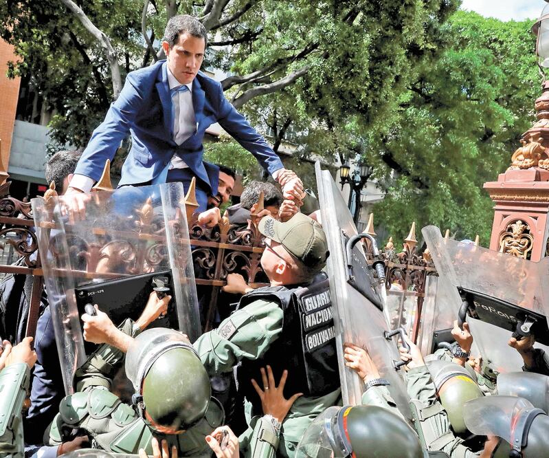 El líder opositor de Venezuela, Juan Guaidó, trató de saltar una verja para llega r a la elección parlamentaria de presidente, pues fue retenido por la policía. Foto/RAYNER PEÑA. EFE