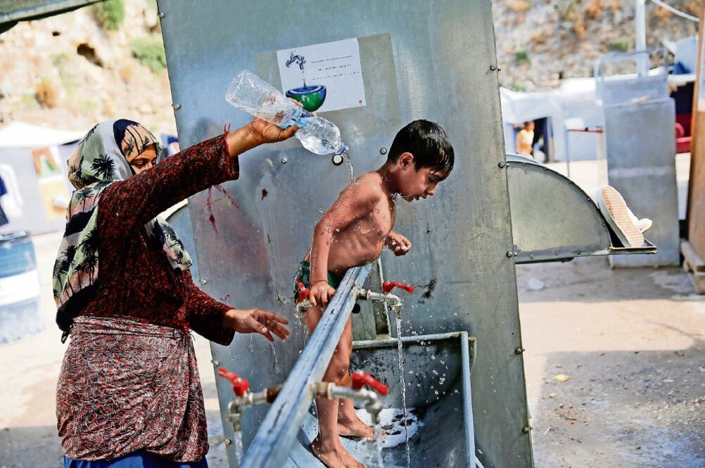Una refugiada siria baña a su hijo de 4 años en el campamento de Chios, Grecia (ALKIS KONSTANTINIDIS. REUTERS)