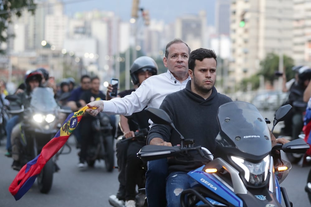 El exdiputado Juan Pablo Guanipa (de camisa blanca) sostiene una bandera de Venezuela durante una caravana tras ser excarcelado este domingo, en Caracas. RONALD PEÑA R. EFE
