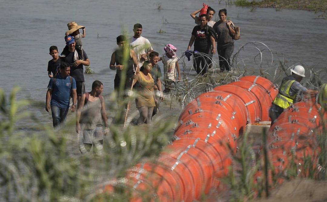 Migrantes que tratan de entrar a Estados Unidos desde México se acercan a un sitio donde trabajadores colocando boyas alambradas de gran tamaño. Foto: AP archivo/EL UNIVERSAL