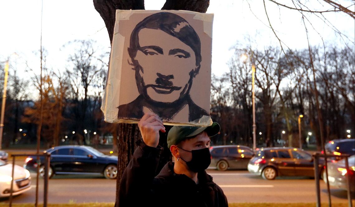 Un activista sostiene una pancarta del presidente ruso, Vladimir Putin, caraterizado como Adolf Hitler, durante una manifestación frente a la embajada de Ucrania en Bucarest, Rumania. Foto: EFE