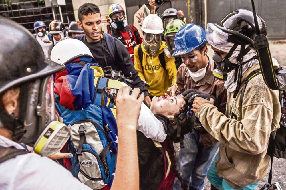 Manifestantes trasladan a un compañero herido durante las manifestaciones de ayer en Caracas. Los participantes se enfrentaron con piedras a las fuerzas de seguridad, que lanzaron gases lacrimógenos