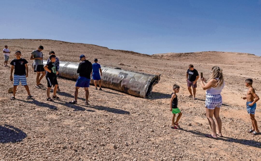 La gente observa los restos de un misil iraní en el desierto del Negev, cerca de Arad, Israel. Foto: Menahem Kahana | AFP