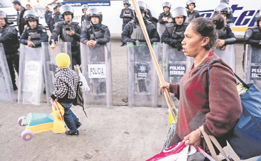Centroamericanos salen de un almacén que usaban como refugio en Tijuana, y que ayer fue clausurado; la policía rodeó el lugar, exhortando a la gente a trasladarse a otro albergue. Foto: GUILLERMO ARIAS. AFP