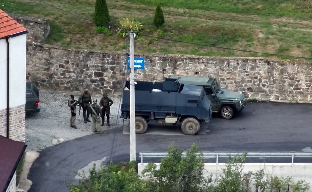 Individuos armados parados junto a un vehículo blindado cerca de la entrada al monasterio de Banjska ocupado por hombres armados, en la aldea de Banjska en el norte de Kosovo. Foto: AFP