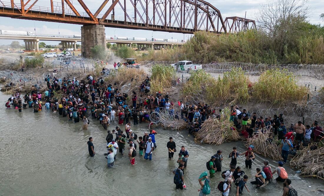 Foto aérea que muestra a los migrantes esperando en el Río Grande a que corten la alambrada de púas para poder cruzar hacia Eagle Pass, en Texas. FOTO: AFP