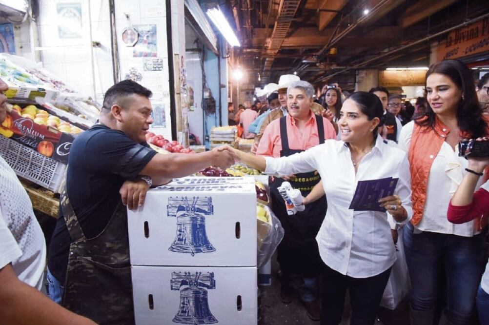 Entre rechiflas de los inconformes porque el equipo de Alejandra Barrales entorpecía el trabajo en la Central de Abasto, la candidata de Por la Ciudad de México al Frente recorrió el área de verduras y regaló mandiles naranja de MC (ESPECIAL)