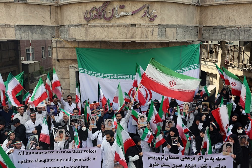 Personal médico protesta contra los ataques de Estados Unidos e Israel, frente al destruido hospital Gandhi, en Teherán. FOTO: EFE