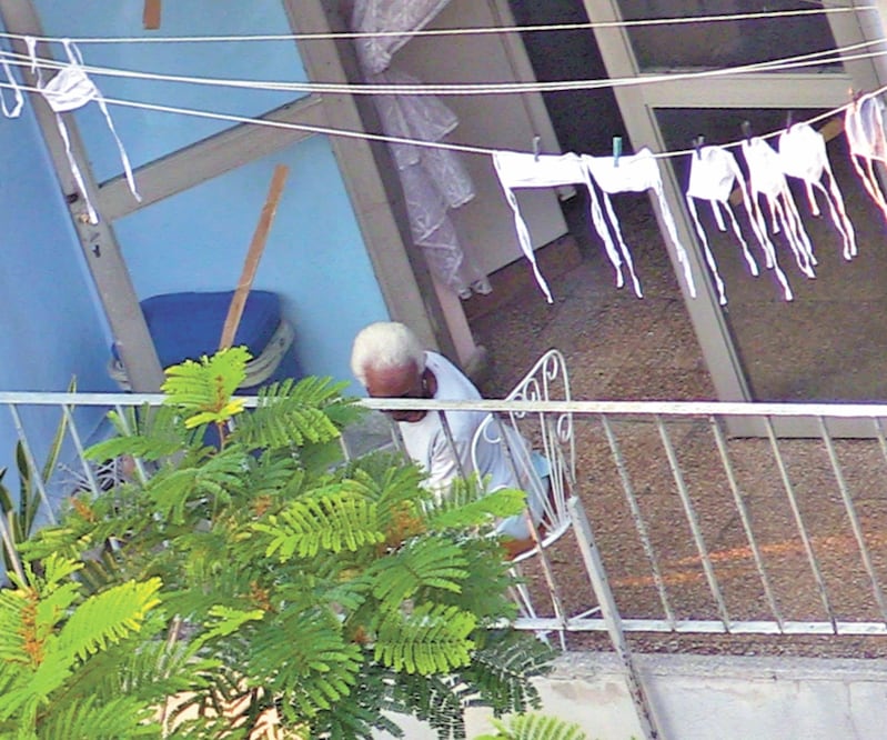 Un cubano permanece en un balcón en La Habana junto a una serie de mascarillas que fueron lavadas y colgadas para secarlas y reutilizarlas. Foto: CORTESÍA 14YMEDIO