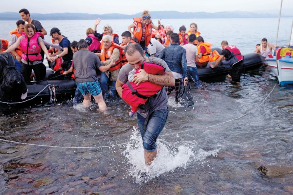 Refugiados sirios llegan a la isla griega de Lesbos en un bote inflable después de cruzar el mar desde Turquía (PETROS GIANNAKOURIS. AP)