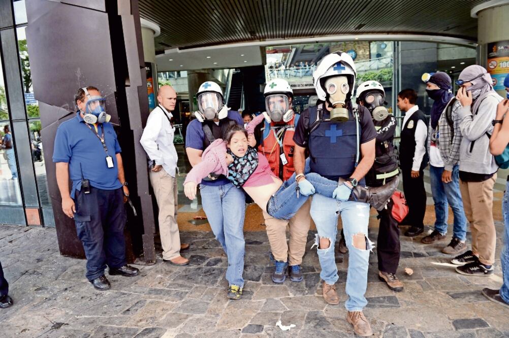 Médicos voluntarios sacan a una joven afectada por los gases lacrimógenos lanzados por efectivos venezolanos en el centro comercial Sambil, el principal de Caracas, ayer (FEDERICO PARRA. AFP)
