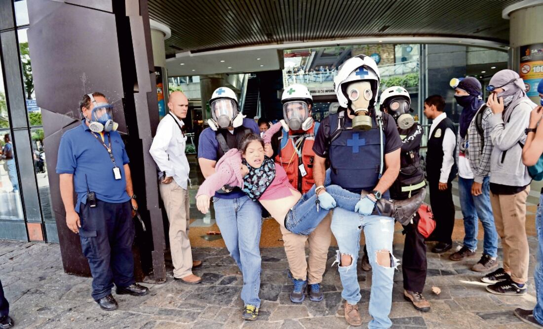 Médicos voluntarios sacan a una joven afectada por los gases lacrimógenos lanzados por efectivos venezolanos en el centro comercial Sambil, el principal de Caracas, ayer (FEDERICO PARRA. AFP)