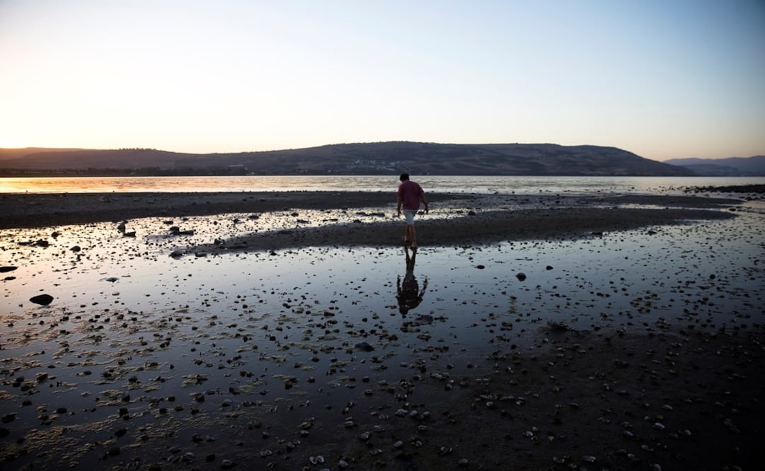 A man walks towards an island that has materialized at the southern edge of the Sea of Galilee in northern Israel - Photo: Ronen Zvulun/REUTERS