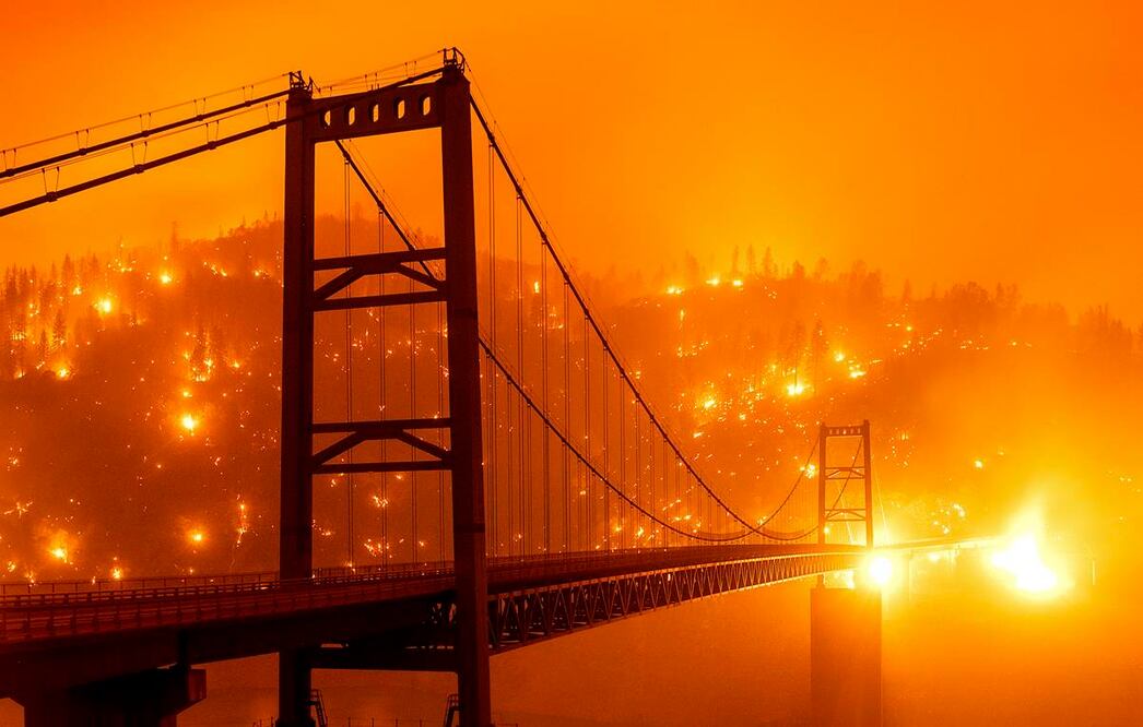 Fotografía tomada con velocidad baja que muestra brasas iluminando una colina detrás del puente Bidwell Bar en Oroville, California, la noche del miércoles 9 de septiembre de 2020. (AP Foto/Noah Berger)