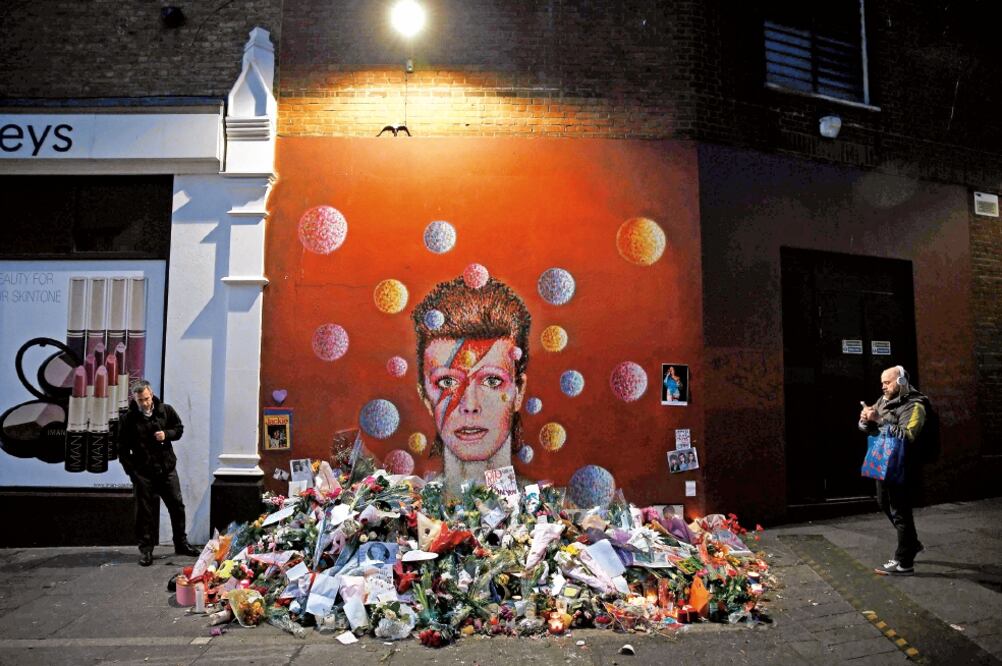 El mural de David Bowie en el barrio londinense de Brixton; sus seguidores han erigido un altar con flores, velas y fotografías para recordarlo (FOTOS: REUTERS Y AP)