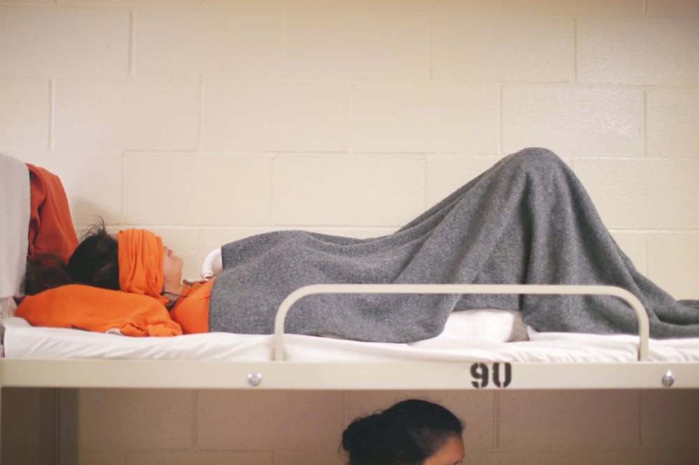 Una inmigrante descansa en el dormitorio de un centro de detención, en Adelanto, California (ARCHIVO. REUTERS)