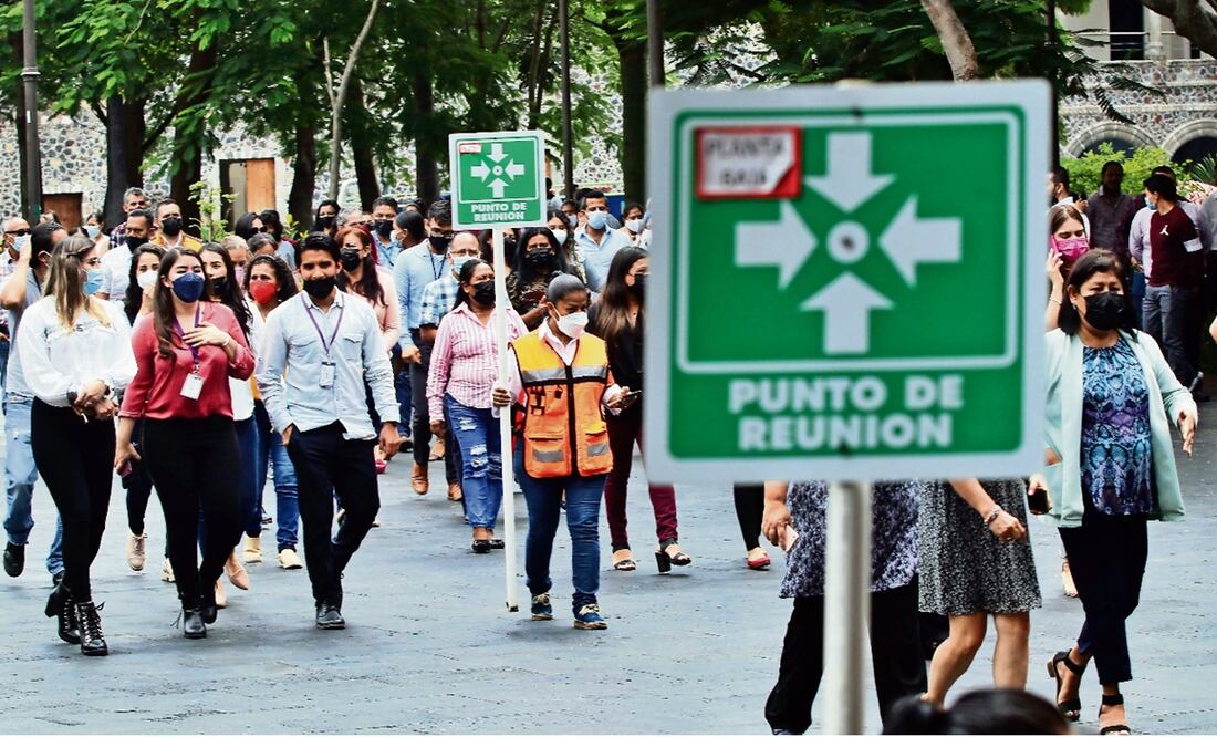 Trabajadores del poder ejecutivo salen de las oficinas del Palacio de Gobierno durante el simulacro nacional.