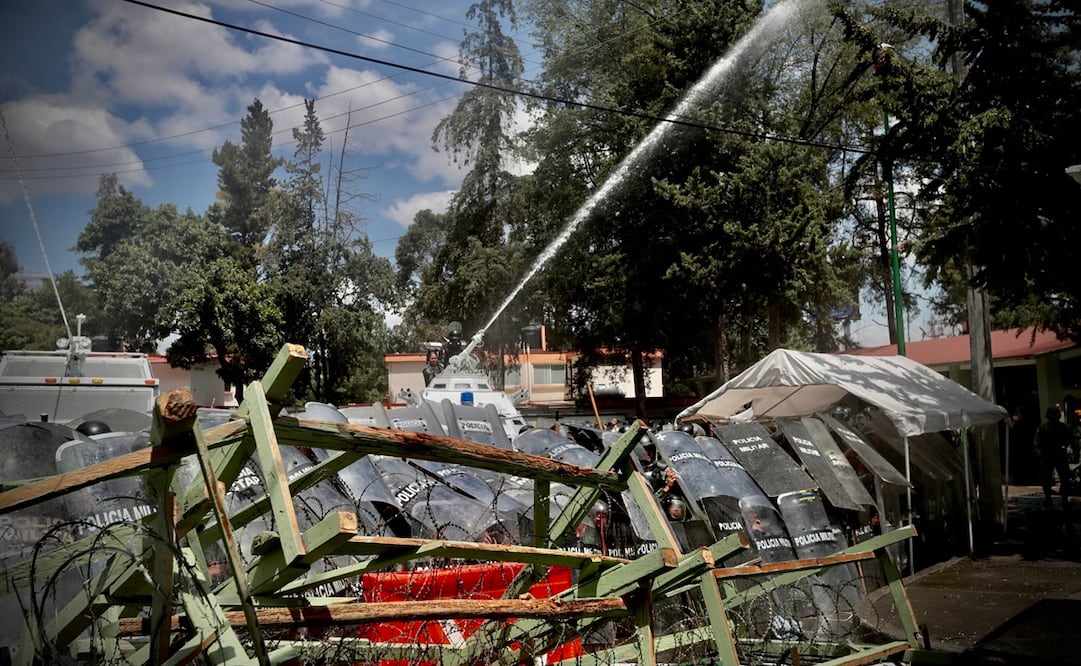 Al finalizar el mitin de los padres de los normalistas, jóvenes comenzaron a lanzar piedras y petardos contra policías. También desprendieron algunas rejas.