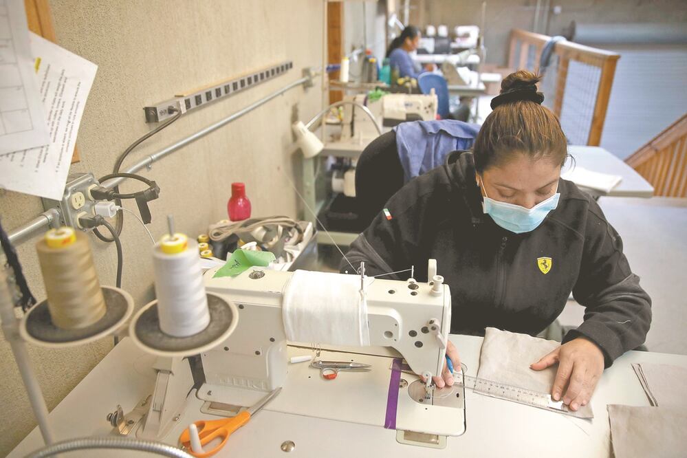 Una empleada de Rough Linen hace cubrebocas para hospitales. Foto: AFP