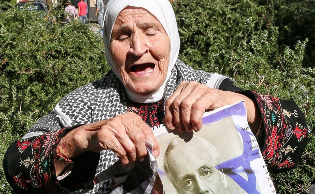 Una mujer palestina sostiene una fotografía partida en dos de Arthur Balfour durante una protesta en la embajada británica en Beirut. (EFE)