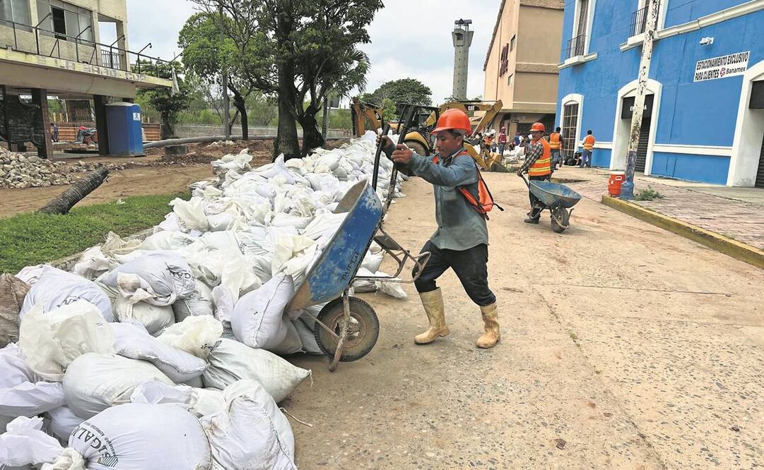 Trabajadores colocan costales con arena alrededor de casas para evitar inundaciones. Foto: Luma López/EL UNIVERSAL