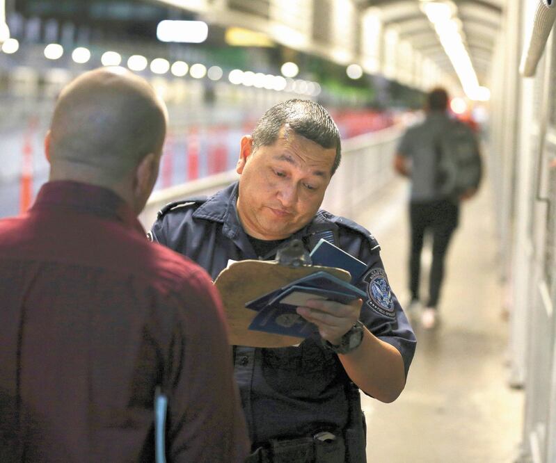Un agente fronterizo revisa los documentos de un migrante que busca solicitar asilo en Estados Unidos, en el Puente Internacional 1. FERNANDO LLANO. AP
