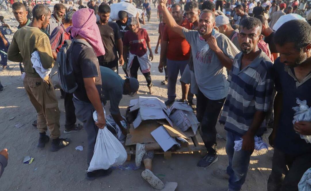 Palestinos, junto al cuerpo de una mujer que fue golpeada por un camión cuando intentaba alcanzar un camión en un convoy de ayuda humanitaria que circulaba por el corredor de Morag, cerca de Rafah, en el extremo sur de la Ciudad de Gaza, el 4 de agosto de 2025. Foto: AP