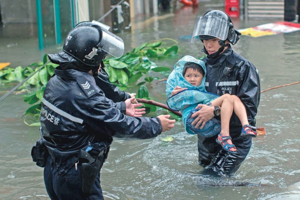 Policías rescatan a un niño en una calle inundada en el barrio de Lei Yu Mun, en Hong Kong, por el tifón Mangkhu t , que ha dejado unas 200 personas heridas a su paso por la ciudad. (JEROME FAVRE. EFE)