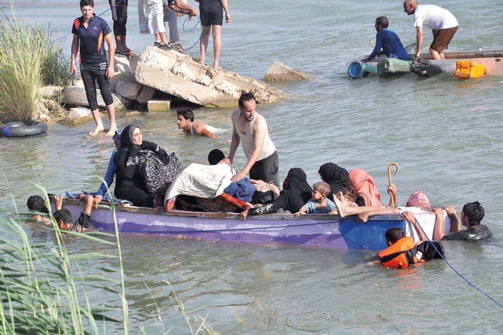 Civiles desplazados de Faluya por los combates entre el ejército iraquí, que busca recuperar el control de la ciudad, y el Estado Islámico (EI) cruzan el río Éufrates, en un intento por ponerse a salvo (AP)