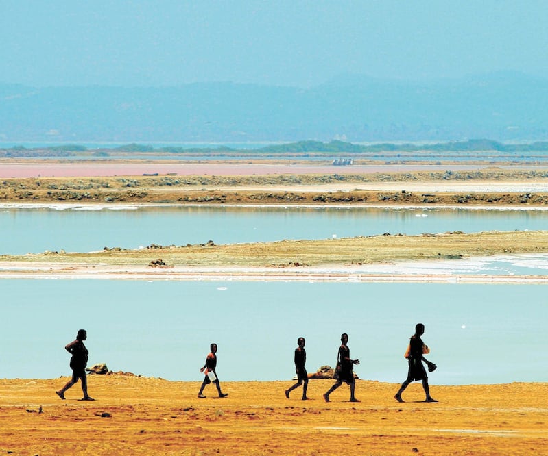Una familia camina al lado de las piscinas en las que se cosecha sal en el corregimiento de Galerazamba, Bolívar, al norte de Colombia, donde la ocupación hotelera es de apenas 3%. Foto: RICARDO MALDONADO. EFE