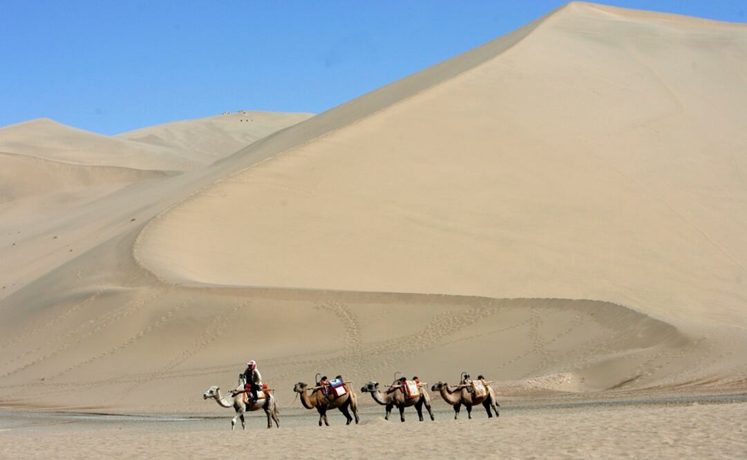 Turistas chinos cruzan en camello el desierto en Dunghuang,  un importante punto de intercambio de China con el mundo exterior durante las dinastías Han y Tang. Foto: Archivo