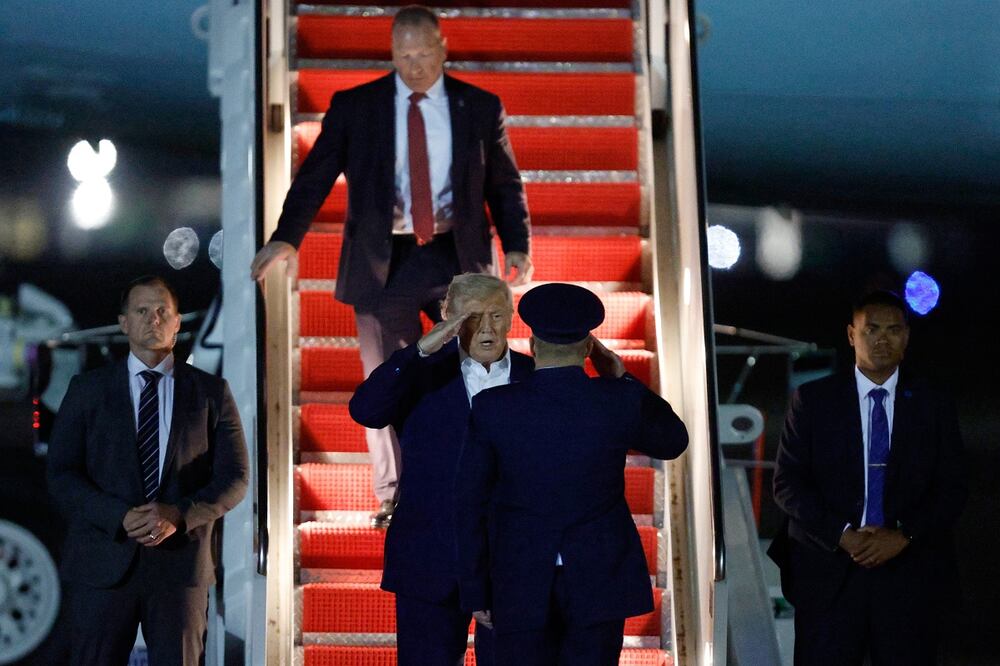 El presidente Donald Trump (centro) es recibido por el coronel Paul Pawluk, vicecomandante de la 89.ª Ala de Transporte Aéreo (centro derecha), tras bajar las escaleras del Air Force One a su llegada a la Base Conjunta Andrews, Maryland, el viernes. Foto: AP
