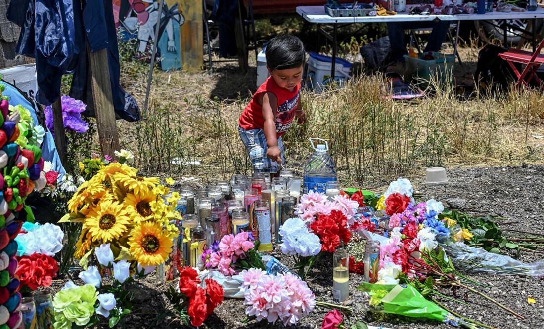 Un niño enciende una vela mientras visita un monumento improvisado en el lugar donde se descubrió un camión con migrantes adentro, en San Antonio. Foto: AFP
