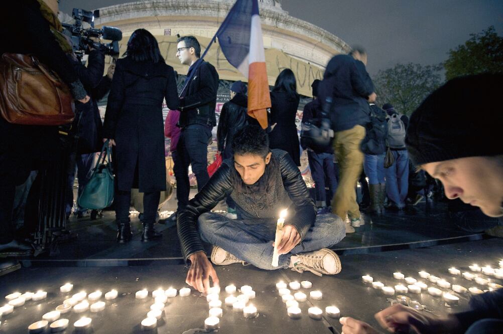 Un parisino coloca velas en un memorial en tributo por las víctimas del viernes pasado, en la Plaza de la República, en París. OEL SAGET. AFP