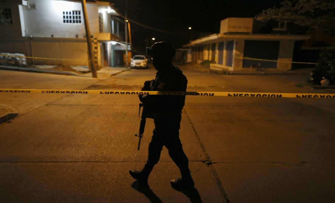 An officer patrols along a border of caution tape - Photo: Rebecca Blackwell/AP