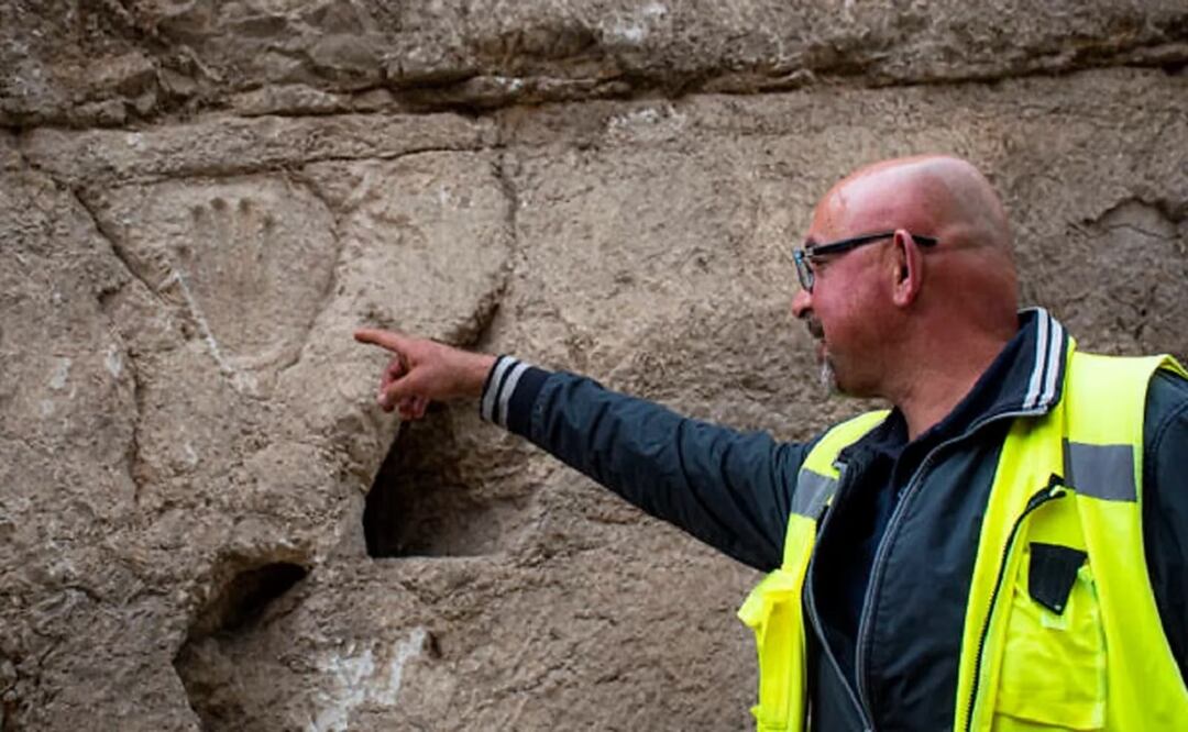 Zubair Adawi, director de excavación de la Autoridad de Antigüedades de Israel, señala una huella de mano tallada descubierta en un antiguo muro de foso alrededor de la Ciudad Vieja de Jerusalén. Foto: Autoridad de Antigüedades de Israel