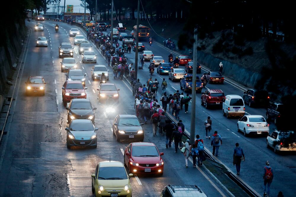 Migrantes hondureños caminan entre el tráfico hacia el departamento de Escuintla para acercarse a la frontera con México. Foto: EFE