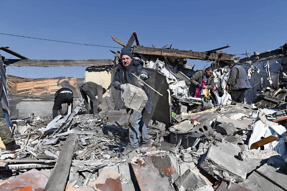 Residentes al limpiar los escombros, tras los bombardeos en el asentamiento de Hanzhenkova. Foto de
AFP