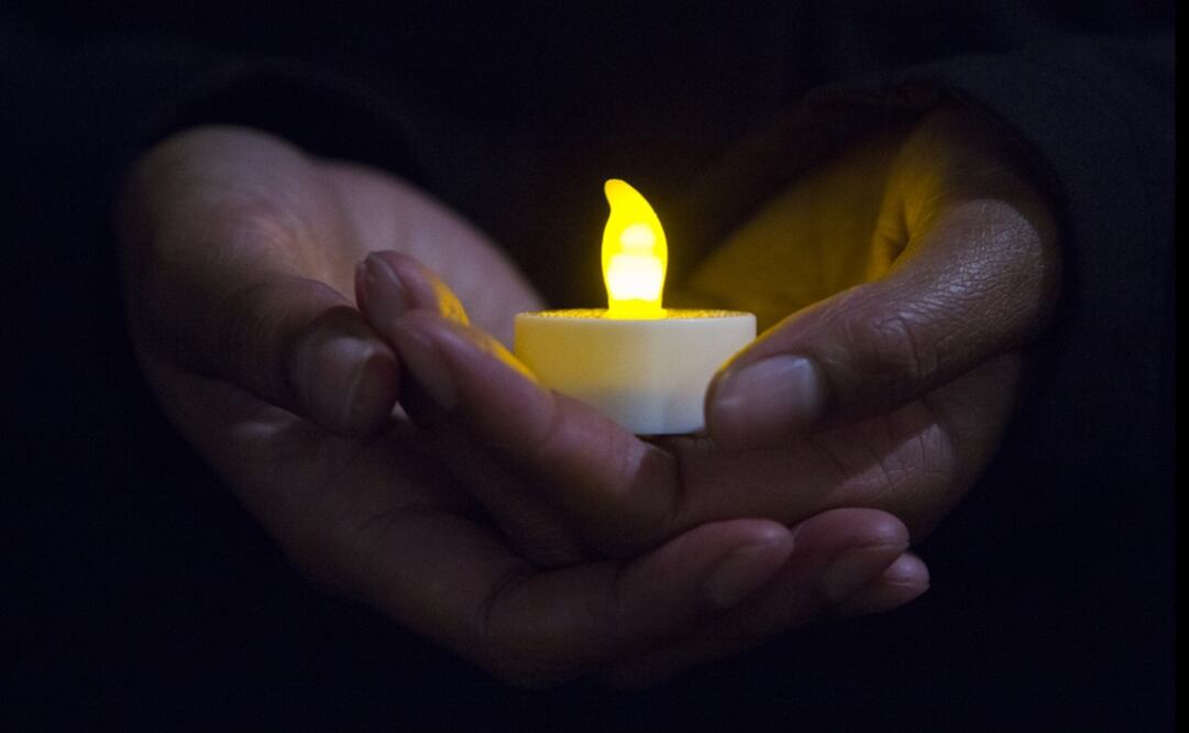 A person holds a candle - Photo: Kaylee Everly/AP Photo