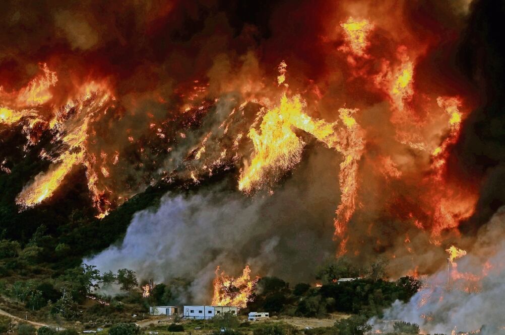 Las llamas en las montañas de San Bernardino, y los fuertes vientos, amenazan casas rodantes ubicadas en el lugar, en California (PATRICK T. FALLON. REUTERS)